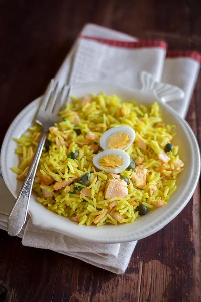 Traditional Scottish dish Kedgeree with basmati rice, curry powder, hot smoked salmon, capers served with hard boiled eggs in a plate for breakfast, selective focus