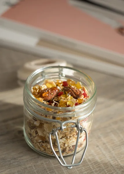 Homemade granola with oat flakes, honey, brown sugar, nuts and dried fruits in a jar, selective focus