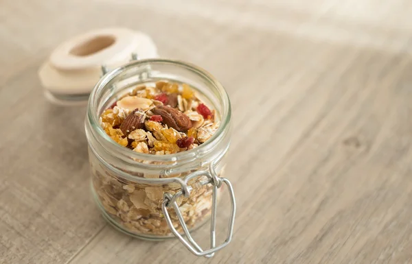 Homemade granola with oat flakes, honey, brown sugar, nuts and dried fruits in a jar, selective focus