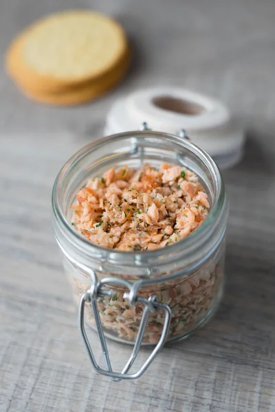 Roasted and smoked salmon and soft cheese spread with dill and butter served with cheese crackers, selective focus