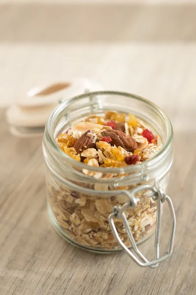 Homemade granola with oat flakes, honey, brown sugar, nuts and dried fruits in a jar, selective focus