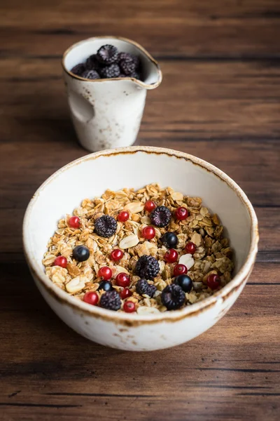 Homemade granola or muesli with toasted peanuts, blackberry and black and red currant in a bowl for healthy breakfast, selective focus