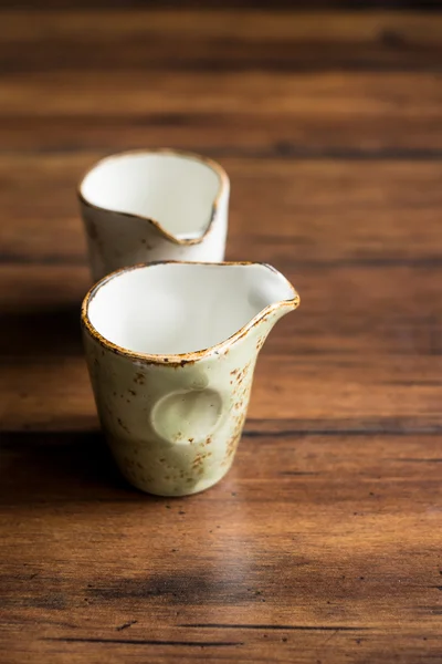 Empty clean plates and cups isolated on dark brown wooden rustic board, selective focus