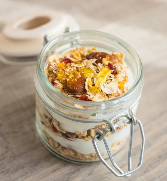 Homemade bircher muesli with toasted rolled oats, dried fruits, nuts, honey and fresh yogurt in a jar, traditional Switzerland breakfast meal, selective focus