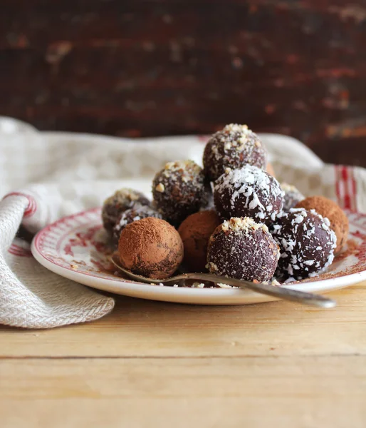 Chocolate truffles with chopped nuts, shredded coconut and cocoa powder on a dessert plate