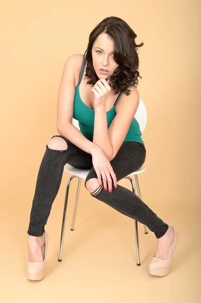 Attractive Young Woman Sitting on a Chair in High Heel Shoes and