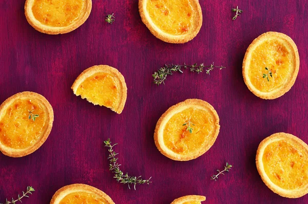 Tartlets with lemon filling and thyme on deep lilac background