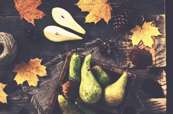 Fall decoration with yellow pears in rustic crate, maple leaves,