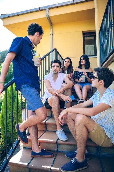 Young people talking outdoors sitting on home stairs steps