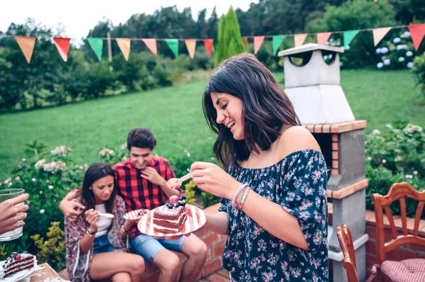 Woman eating piece of cake in summer party