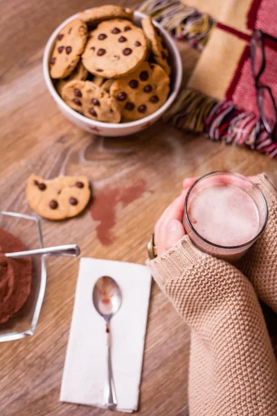 Female hands with hot drink and chocolate cookies