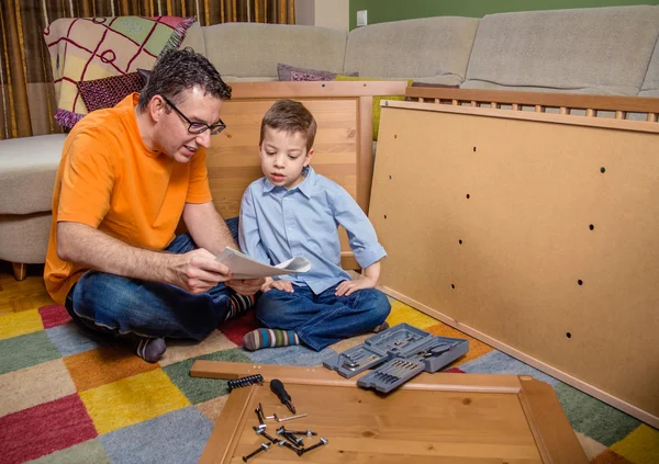 Father and son reading instructions to assemble furniture