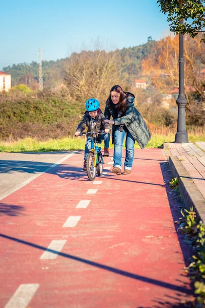 Mother teaching son to ride a bike in cycleway