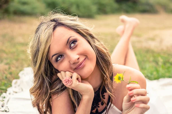 Romantic girl with flower in the hand dreaming outdoors