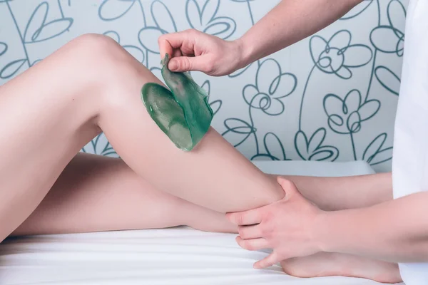 Beautician hands doing depilation in woman legs with hot wax