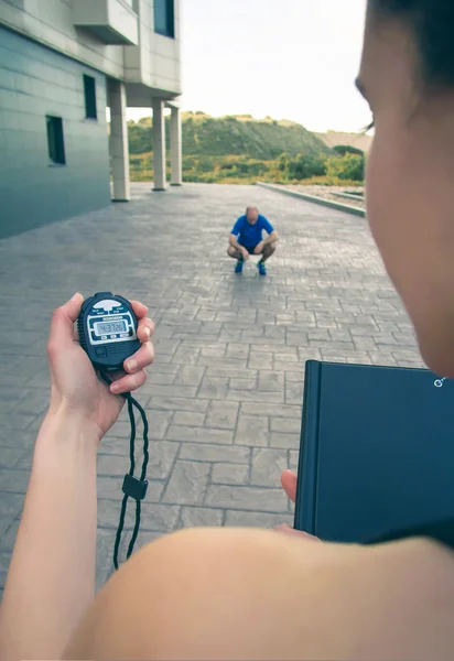 Trainer hand using chronometer to timing man training