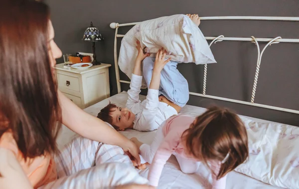 Relaxed mother and sons playing over the bed