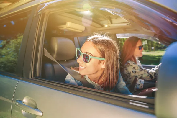 Happy young woman looking back through the window car