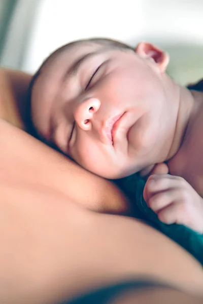 Newborn baby sleeping peacefully over the mother chest