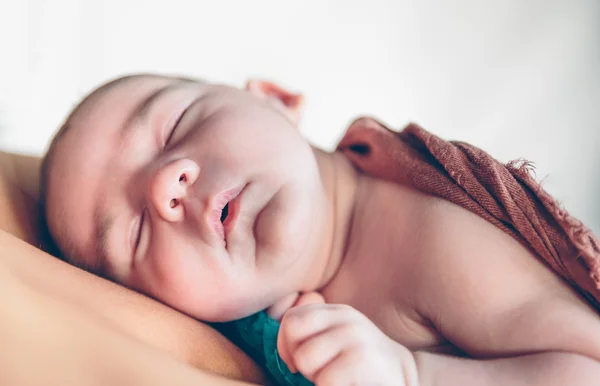 Newborn baby sleeping peacefully over the mother chest