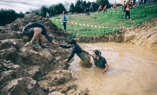 Team helping to cross mud pit in a test of extreme obstacle race