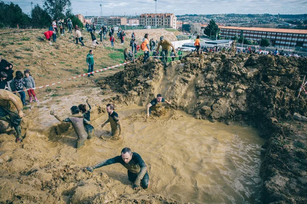 Runners crossing mud pit in a test of extreme obstacle race