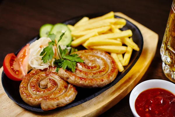 Roasted sausages in a frying pan on wooden table