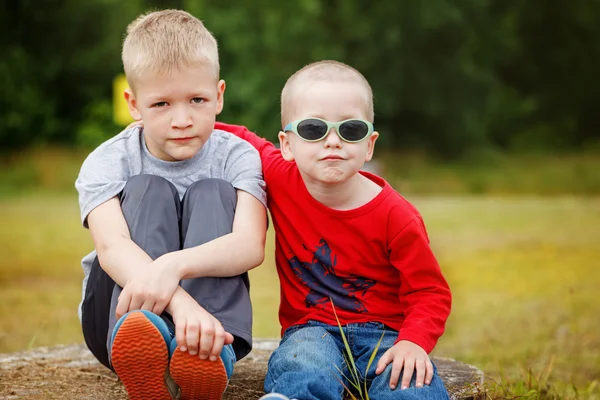 Two little sibling boys hugging and having outdoors. Brothers an