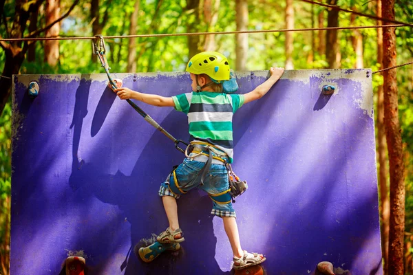 Child climbing on a wall in an outdoor climbing center in summer day