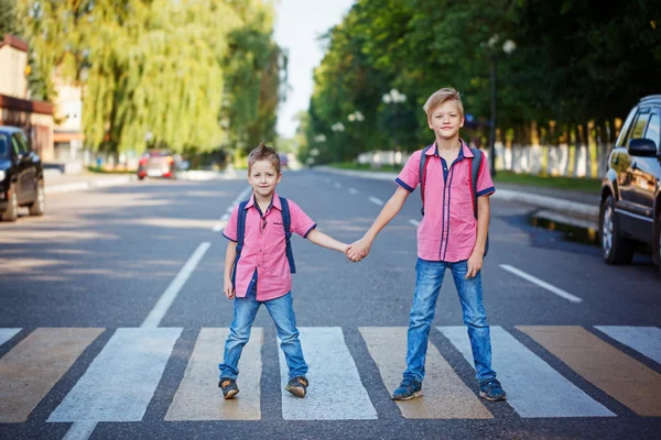 Kids with backpack walking, holding on warm day  on the road .