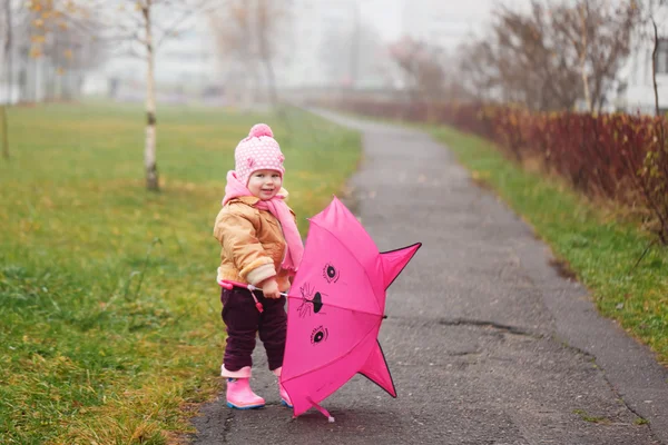 The little girl with an umbrella in the fall in autumn