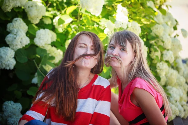 Two happy female friends playing in green grass