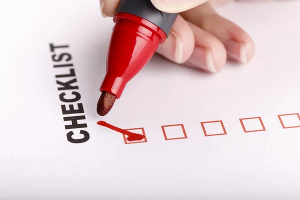 Checklist on white with marker and woman hand