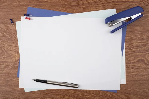 Sheets of paper and office accessories on wooden texture.