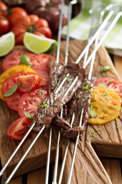 Flank steak on skewers with tomatoes