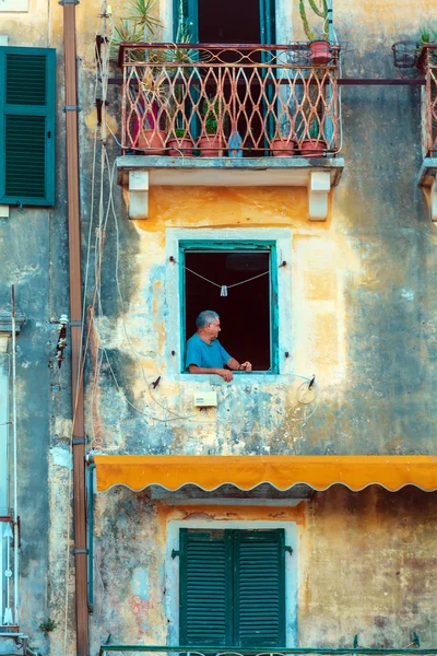 CORFU, GREECE - JULY 6, 2011: Old man in the window of ancient h
