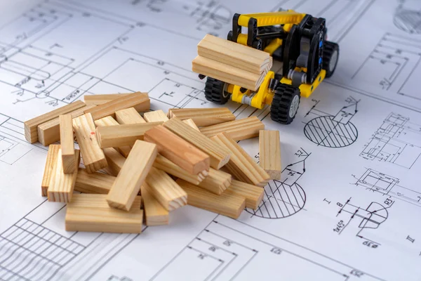 Toy construction machine buildsmodel of house from wooden blocks (bars) at the drawings.