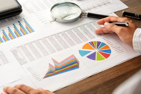 Girl and business accessories (notebook, calculator, planchette, tablet, fountain pen, glasses) and graphics, tables, charts on white sheets on office desk. Soft focus.