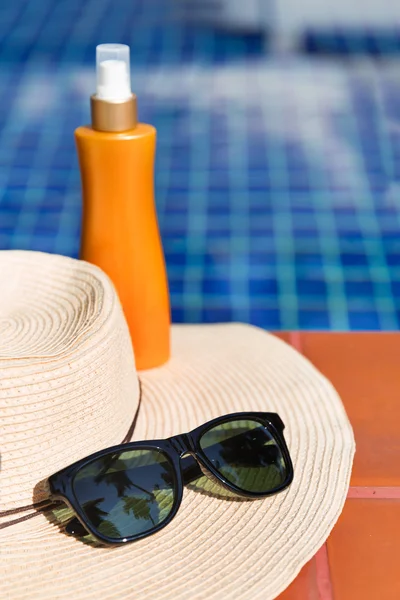 Sunscreen cream and sun glasses with straw hat swimming po
