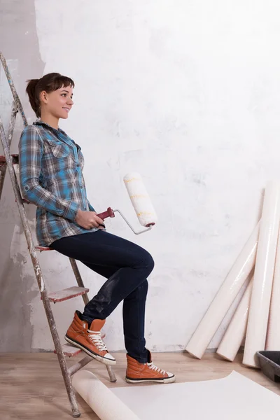 Pretty woman with roller paste wallpaper repair house