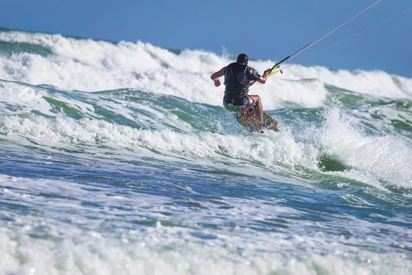 Athletic man riding on kite surf board sea waves