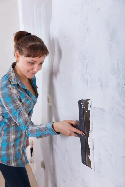 House improvement. woman worker puts stucco on wall