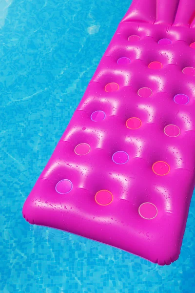 Pink air mattress in swimming pool. Holiday background.