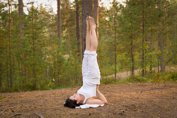 Young woman in Yoga shoulder stand in forest