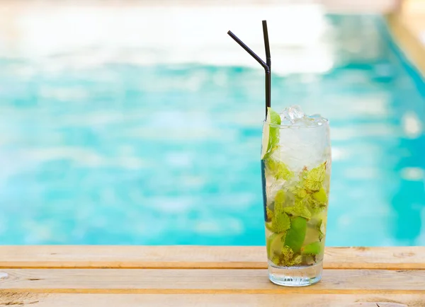 Mohito mojito drink with ice mint and lime near swimming pool