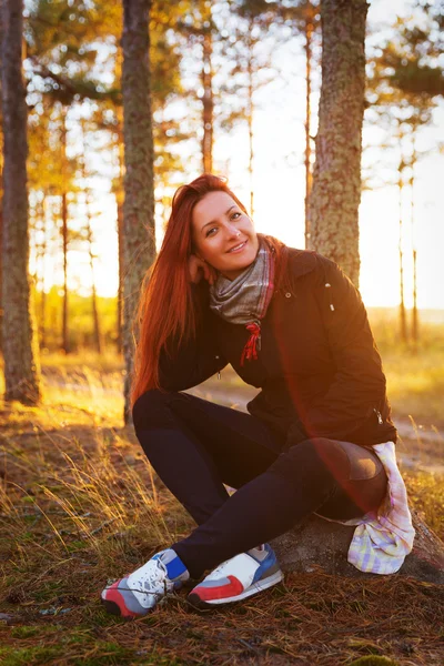 Woman in a sunset lights in autumn forest