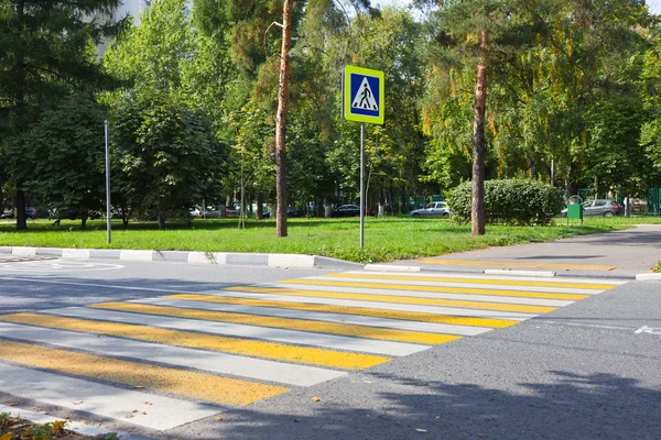 Crossroad with yellow and white stripes and road sign