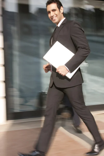 Businessman with a laptop walking