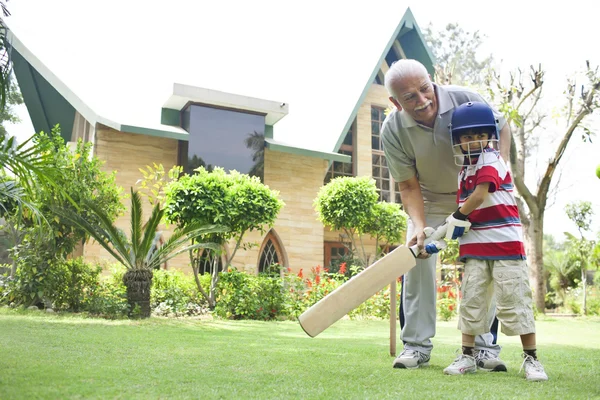 Boy playing cricket with grandfather