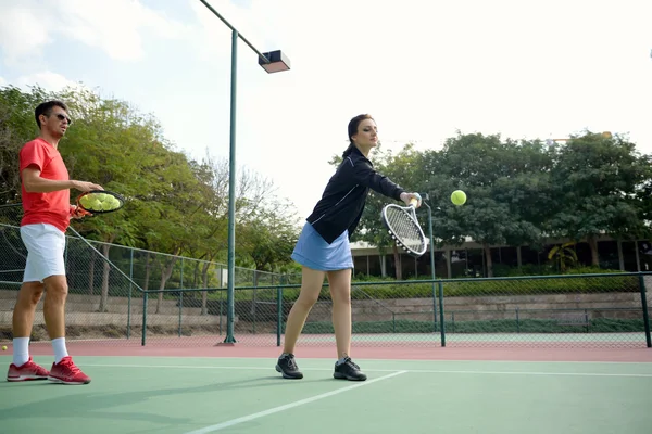 Coach teaching tennis to a woman